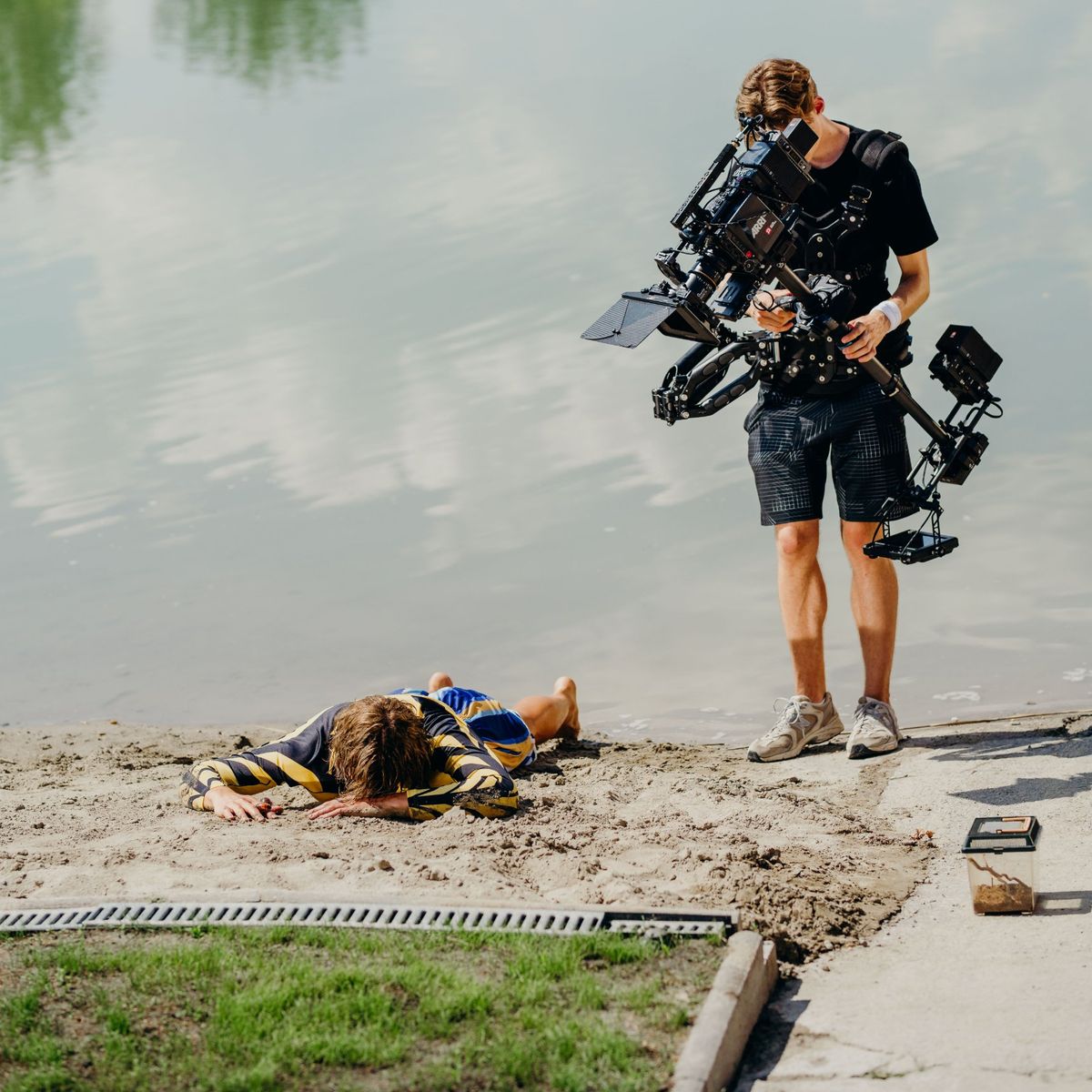 Daniel with the Steadicam at the water's edge while the artist lies face down in the sand