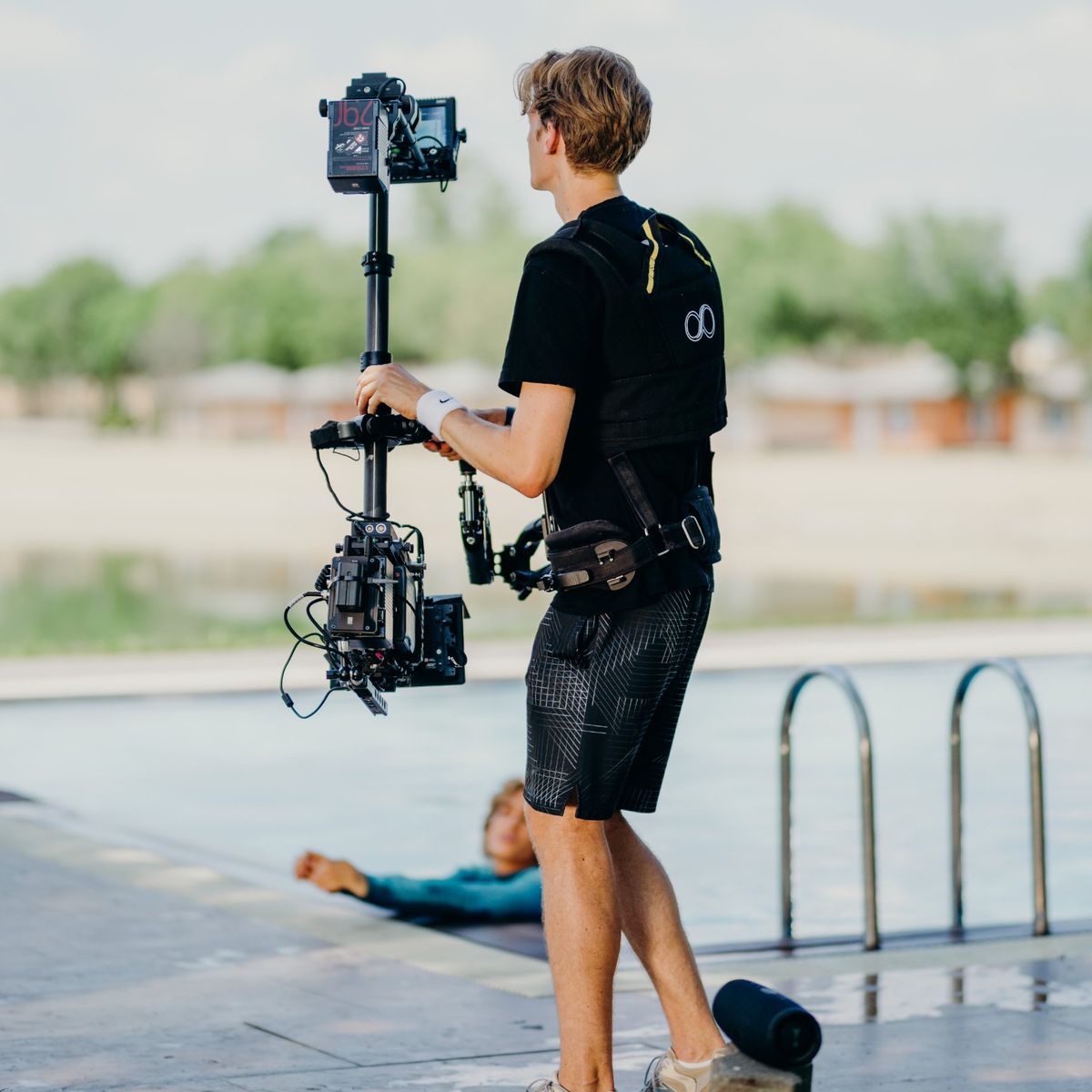 Daniel on the Steadicam at the edge of a pool, the artist leaning on the pool wall